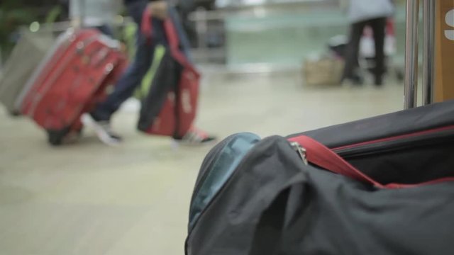 airport luggage cart standing in departure or arrival zone with blurred people at the background waiting for their gate opening. Metal and plastic Hand held shot. Time waste concept