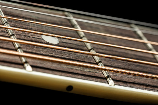 Frets and strings of acoustic guitar on black background. Music wallpaper