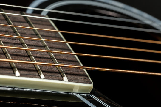 Close-up of metal strings of black acoustic guitar. Music wallpaper