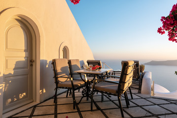 Patio with table and chairs decorated with beautiful bougainvillea flowers at Santorini island, Greece