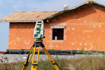 Surveyor measuring equipment (theodolit) on construction site with house in background	
