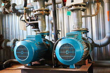 Old blue electric motor with pump, gate valve and pressure gauge on the pipeline.