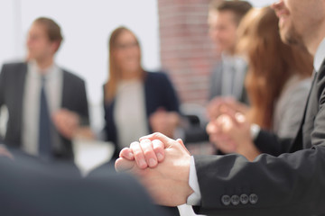 Business group in a circle holding hands indoors