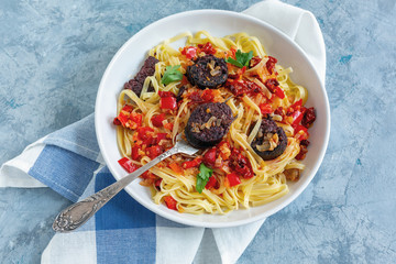 Fork in a plate with Italian pasta and blood sausages.