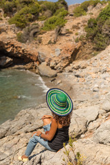 Solo traveller female sitting on the rocks in a beautiful bay