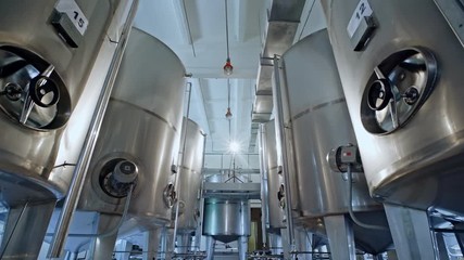 View to shiny metal beer tanks in the room of industrial brewery