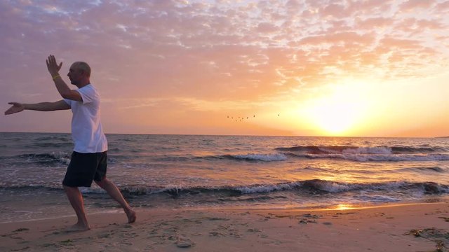 Man training Taijiquan on sea beach during beautiful morning sunrise