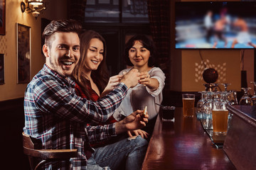 Cheerful multiracial friends enjoying drinks at the bar or pub.