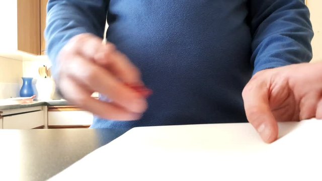 Male with a partially amputated index finger on his right hand putting a red bull dog clip on some white strips of paper
