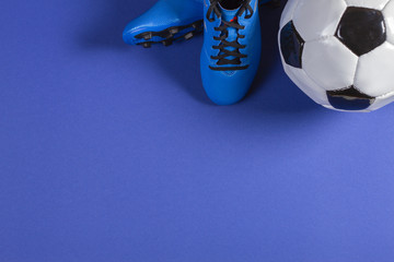 Top view of soccer ball and pair of soccer football sports shoes on blue background