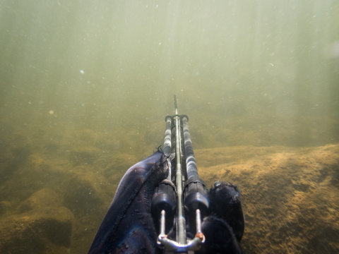 Hand holding speargun underwater Stock Photo