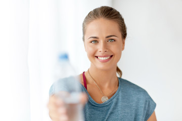 fitness and healthy lifestyle concept - smiling young woman showing bottle of water