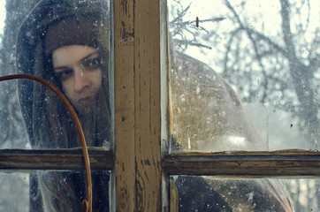 an unkind young woman looks into the window of a village house