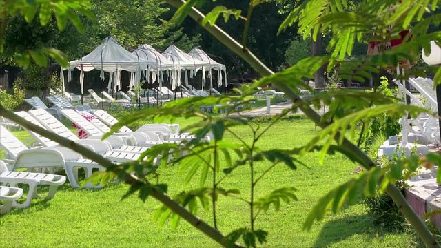 View of luxury spa center with lounge chairs, tent in beautiful and quiet green  garden.