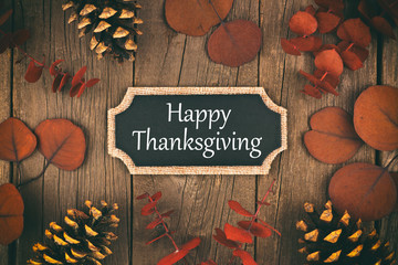 Happy Thanksgiving chalkboard greeting card with red autumn leaves over a rustic wood background