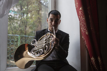 French horn player. Hornist playing brass orchestra music instrument.