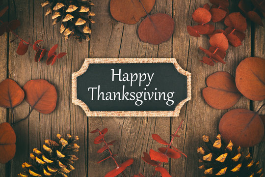 Happy Thanksgiving chalkboard greeting card with red autumn leaves over a rustic wood background