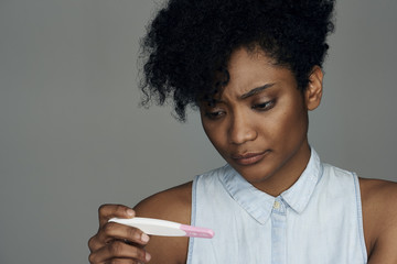 Close-up of young woman looking at pregnancy test strip