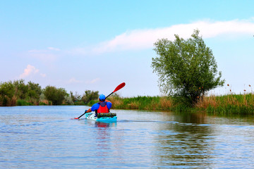 Man paddles a red kayak on the Danube river at summer