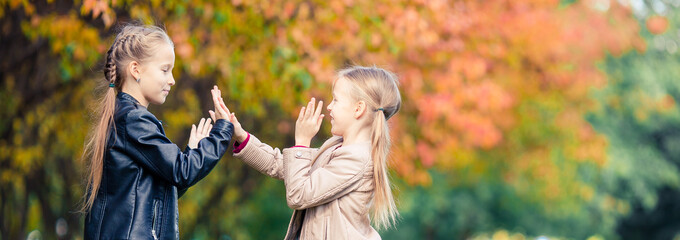Little adorable girls at warm day in autumn park outdoors