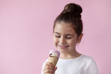 Happy little girl eating ice-cream in a crispy cone. Space for text.