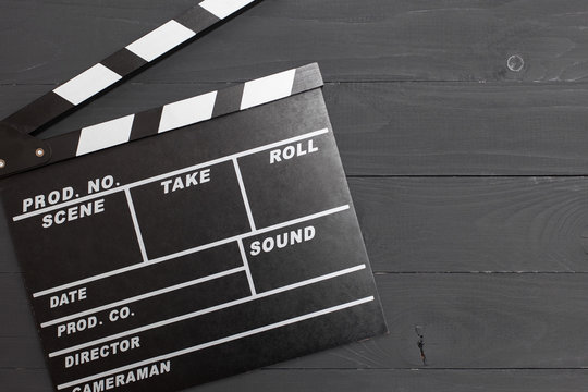 Movie time, flat lay with space for text. Cinema minimal concept. Cinema Clapperboard on a black wooden background.