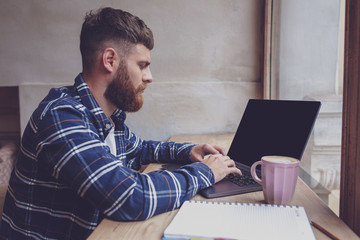 Young man chatting via net-book during work break in coffee shop