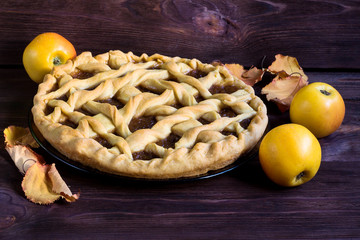 homemade Apple pie on brown wooden background, autumn mood, leaves and apples