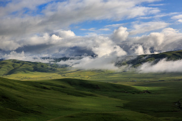 Hongyuan Grassland in Aba Prefecture, Sichuan Province, China. Near Ruoergai Grassland. Mountains, Clouds, Fields of green grass. One of the most beautiful wetland areas in China. Nomadic Lifestyle