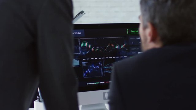 Group of three entrepreneurs analyzing exchange rate statistics using computer software when planning business budget