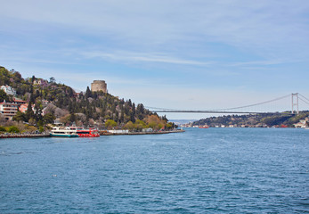 Fototapeta na wymiar Ships passing through Bosphorus Bridge with background of Bosphorus strait on a sunny day with background cloudy blue sky and blue sea in Istanbul, Turkey.