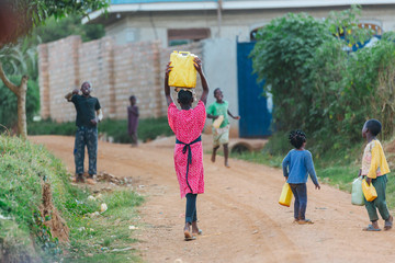 Fototapeta na wymiar children carrying water cans in Uganda, Africa