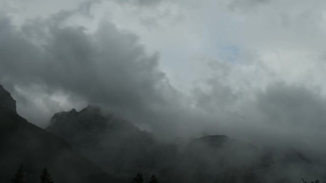 Time lapse of clouds over mountain peak, dramatic stormy sky, forest in foreground, Ojstrica peak in Kamnisko Savinjske Alpe, Logarska dolina, Slovenia, European Alps