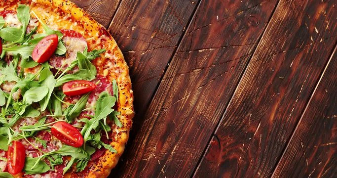 Top view of delicious italian pizza served on dark brown wooden table with copy space