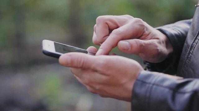 Man uses the phone, scrolls through photos, checks mail. Close-up