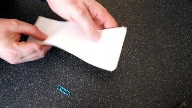 Male with a partially amputated index finger on his right hand putting a blue paper clip on som strips of white paper