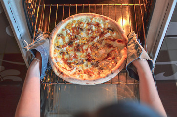 Cooking pizza at home. Taking Pizza out of the oven.