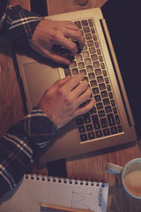 Young man drinking coffee in cafe and using laptop. Man's hands 