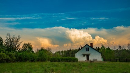 House under stormy sky at sunset