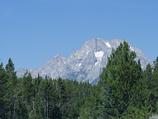 Obraz premium Kontrast bujnych zielonych drzew z surowymi skalistymi i ośnieżonymi kanionami Parku Narodowego Grand Teton w Wyoming.