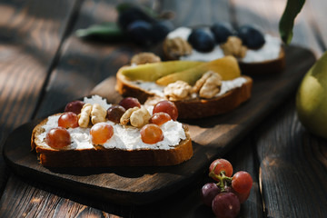 Healthy snacking, homemade delicious crostini with fruits, walnuts and ricotta