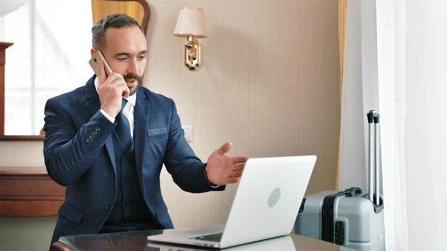 Angry male businessman talking with subordinate employee using smartphone having business trip