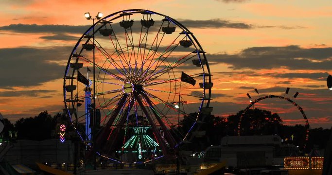 Time lapse slow pan of sunset behind ferris wheel and carnival at the state fair