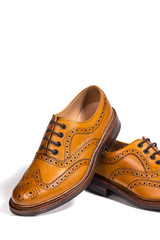 Concepts of Luxury Male Footwear. Partial Closeup of A Pair of Full Broggued Tan Leather Oxfords Shoes. Placed on One Another. Isolated Over White Background.