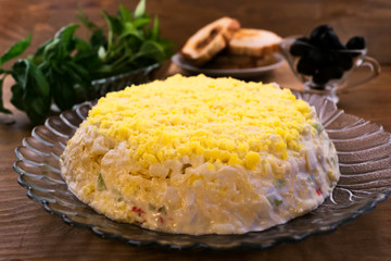 Appetizer of eggs with crab meat, cheese, cucumbers and top layer of egg yolks, basil leaves, toasted, black olives.