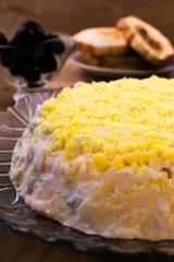 Salad on a round glass plate of egg yolks with cheese, cucumber and crab meat, toast, black olives.