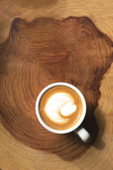 Cup of cappuccino or latte on the wooden stand. Cosy and minimalistic composition. Rustic or country vibes. Simple life concept. Sunlight from a window.