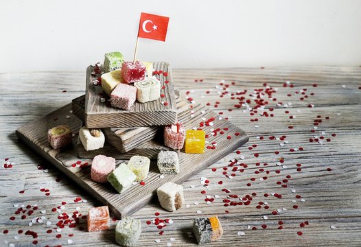 various national Oriental sweets, with paper flags of Turkey, Turkish delight on a wooden white brushed stand and on a white brushed background, horizontal, 