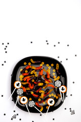 A plate with Halloween sweets on the white background. Children or adult party concept. Flat-lay, top view. Copy space for your text.