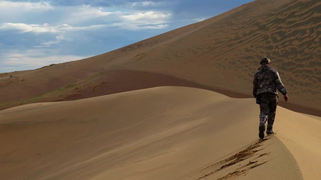 Tourist walking along the edge of the sand dune. Large barkhan in Mongolia sandy dune desert Mongol Els